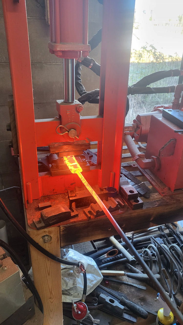 Bladesmith Chris forging a Damascus steel billet on an anvil in his Florida workshop for Fox Trail Craftworks handmade knives collection.