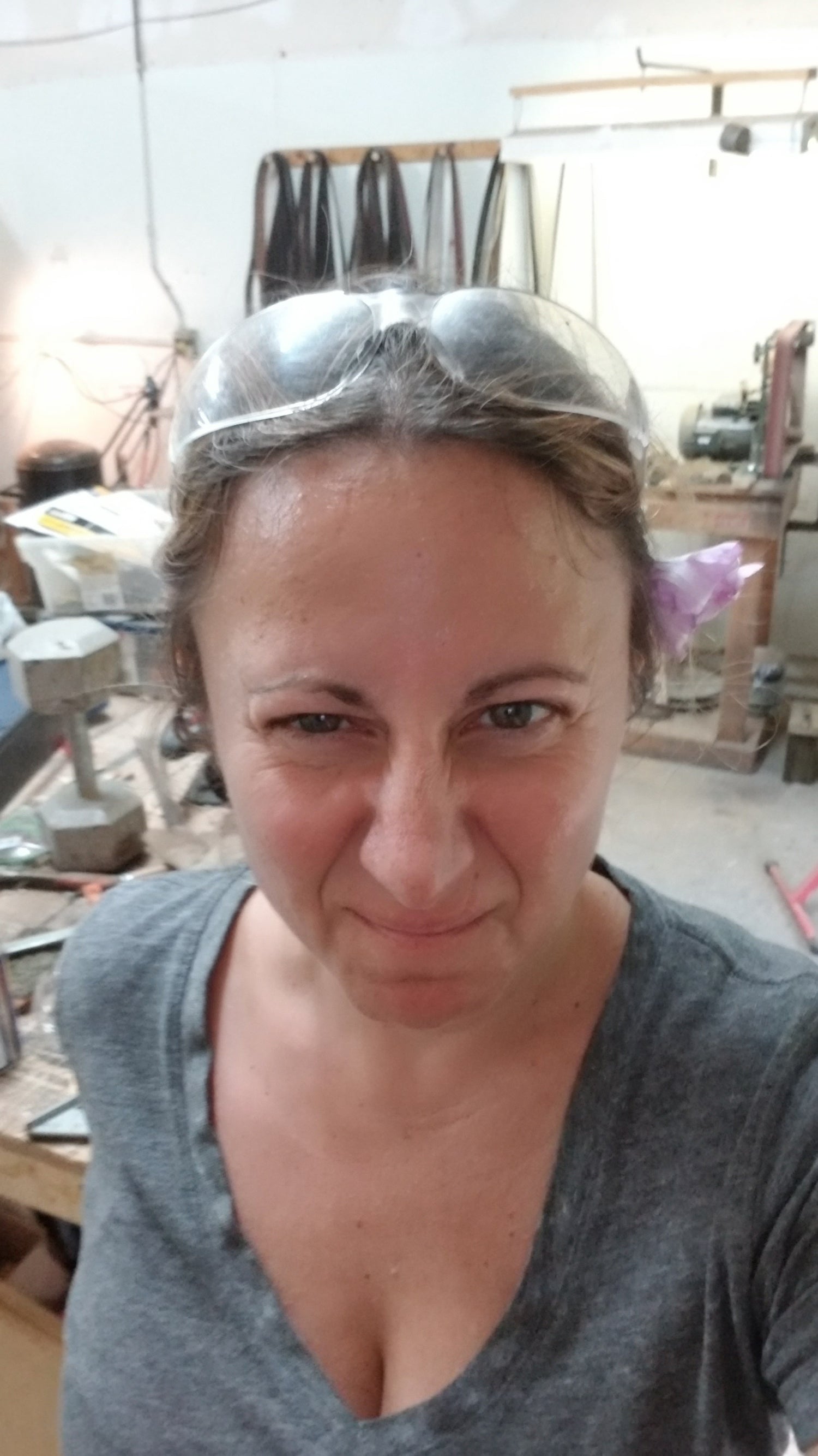 Tami in the Fox Trail Craftworks workshop with safety glasses perched on her head, playfully making her ‘mean face’ after completing her first handmade knife with guidance from bladesmith Chris.