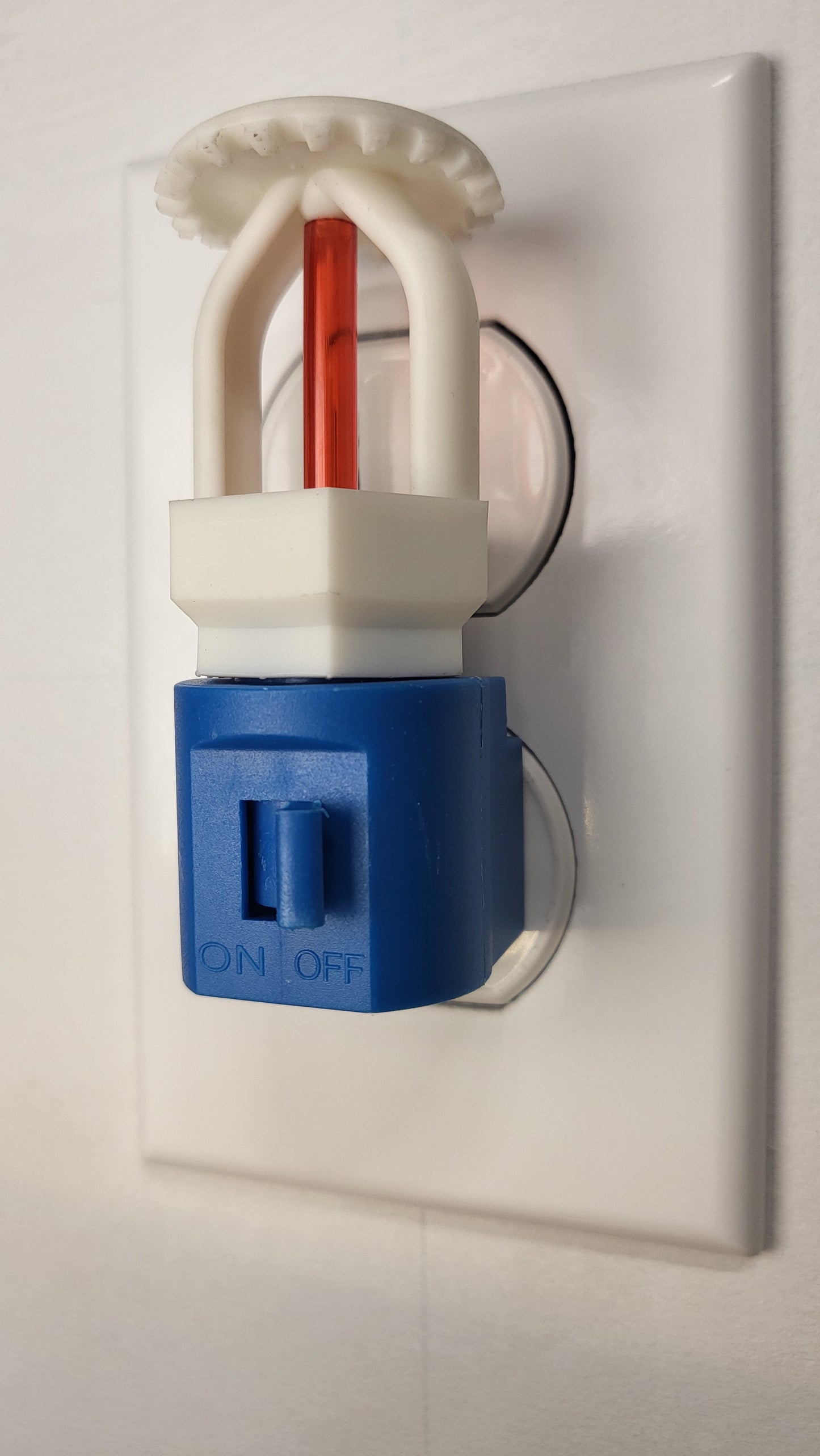 Right‑side view of budget‑friendly fire sprinkler night light with white upright head and red bulb on blue switched base, plugged into wall outlet in off position — ideal for kids or families connected to fire protection.