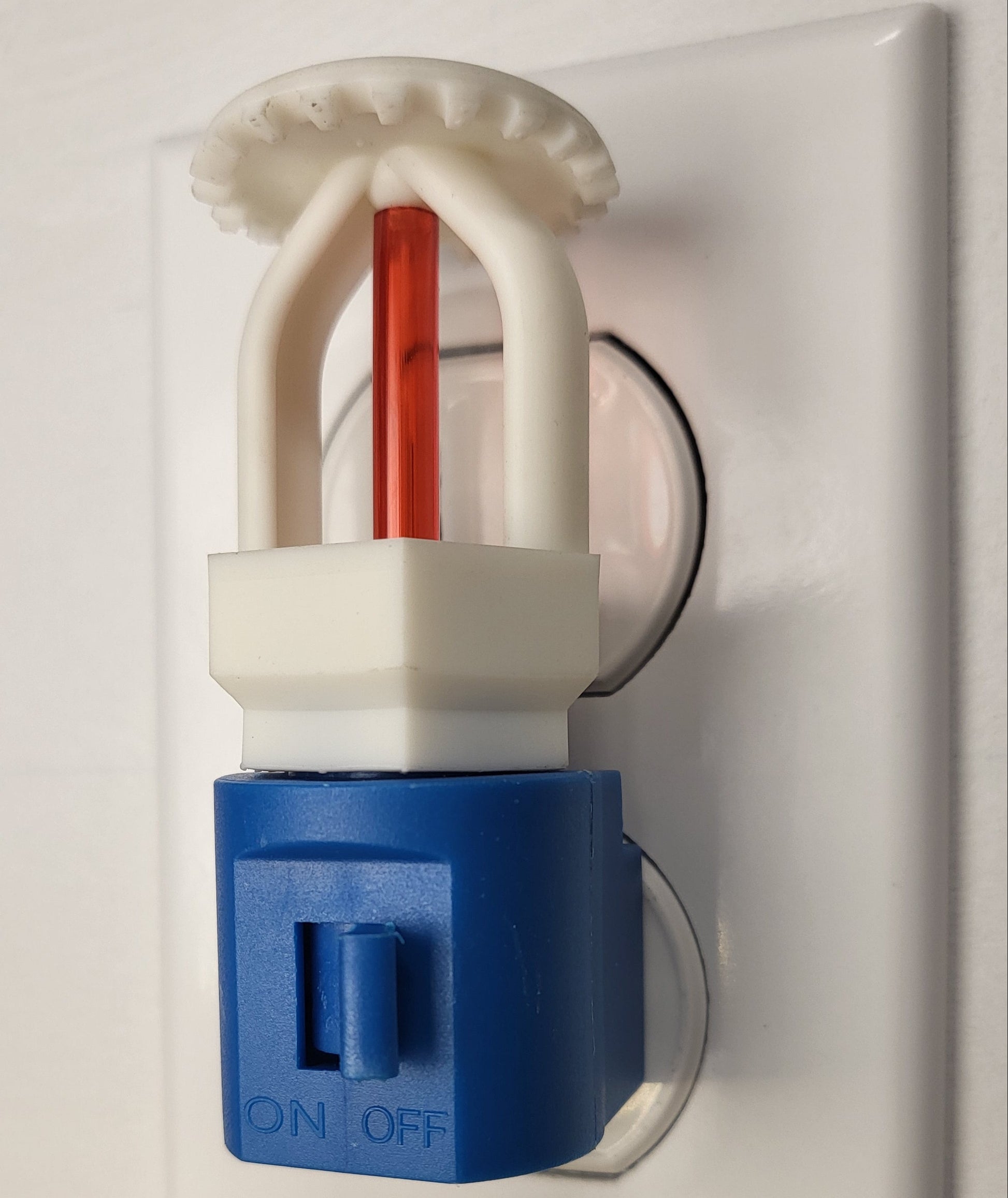 Right‑side view of budget‑friendly fire sprinkler night light with white upright head and red bulb on blue switched base, plugged into wall outlet in off position — ideal for kids or families connected to fire protection.