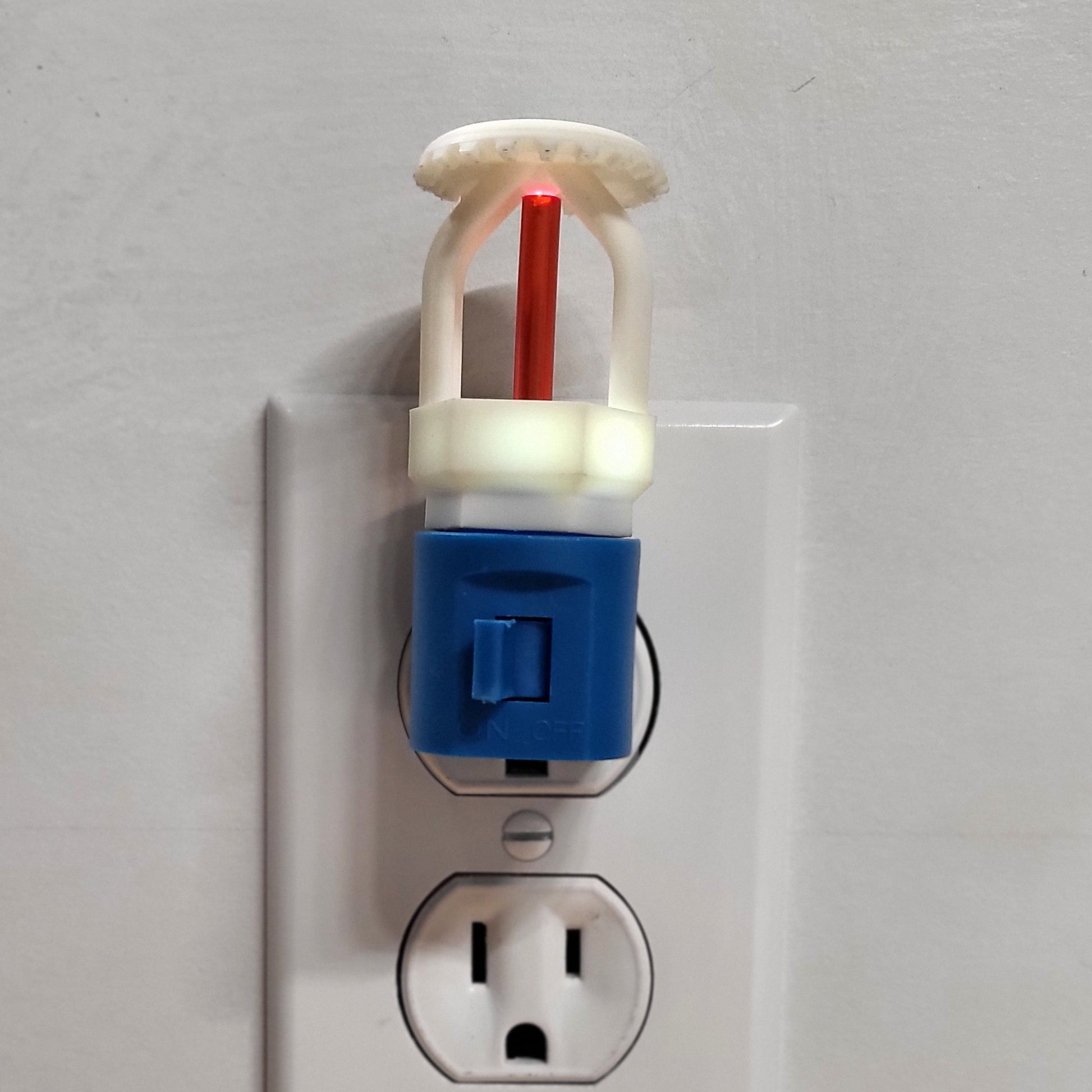 Straight‑on view of  fire sprinkler night light in blue base glowing faintly even in a lit room, white upright head with red bulb reflecting fire protection style for children’s bedrooms or family spaces.