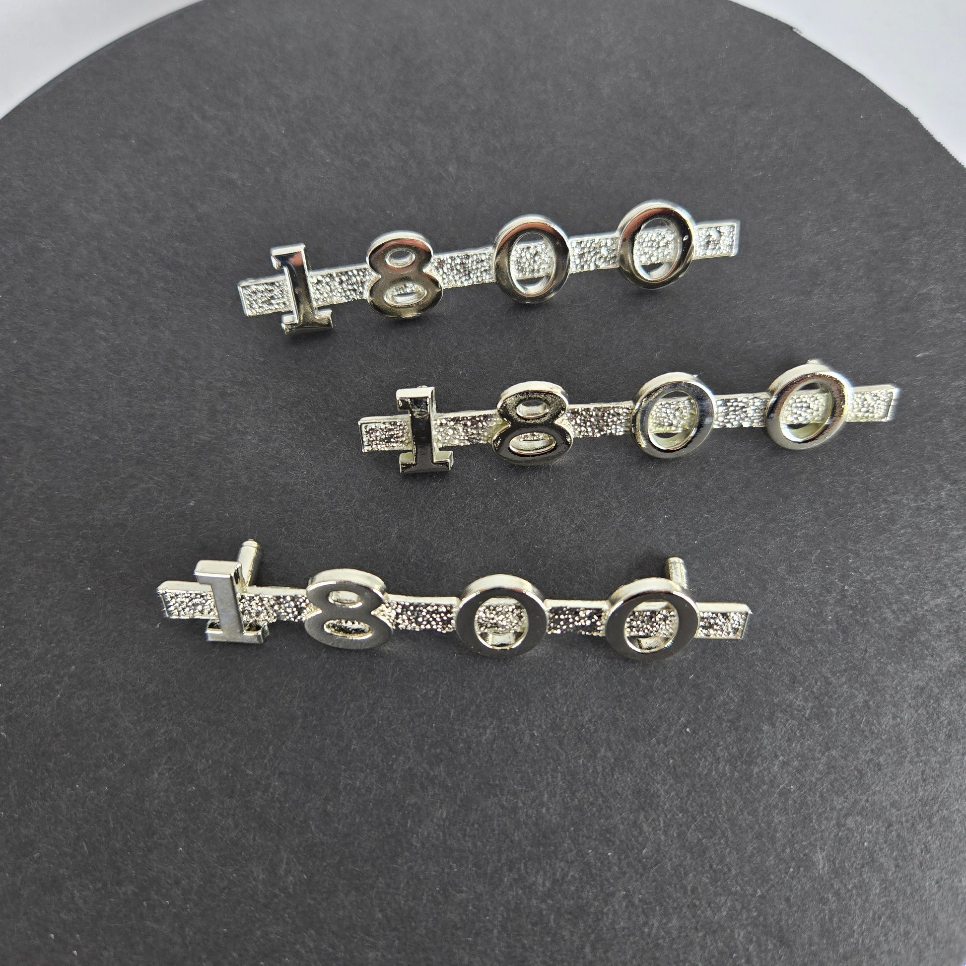 Set of three MGA 1800 custom emblems with mounting pins displayed on black disc with white background, representing complete replacement kit.