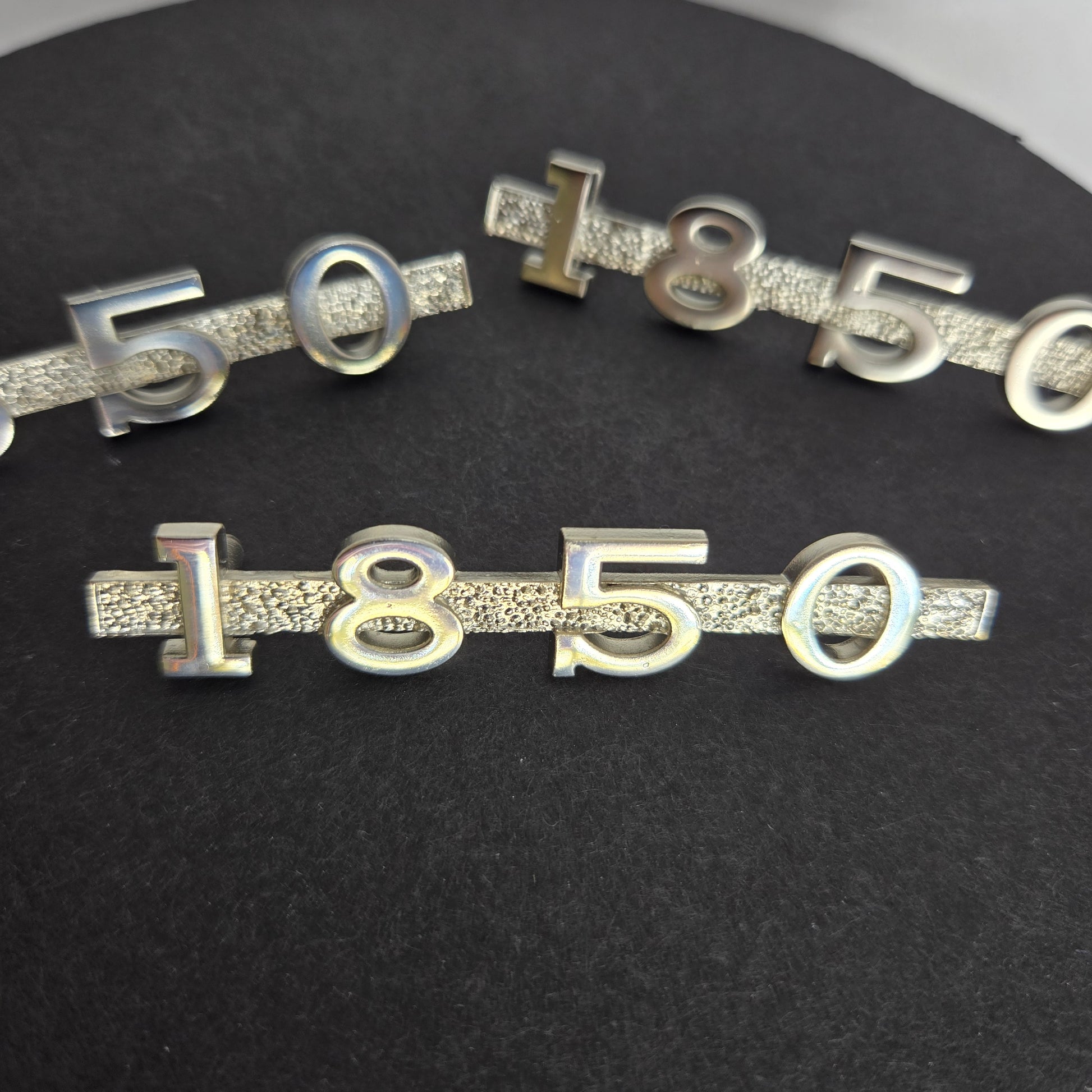 Set of three MGA 1850 custom emblems with mounting pins displayed on black disc and white background, showing exact replacement kit for restorations.