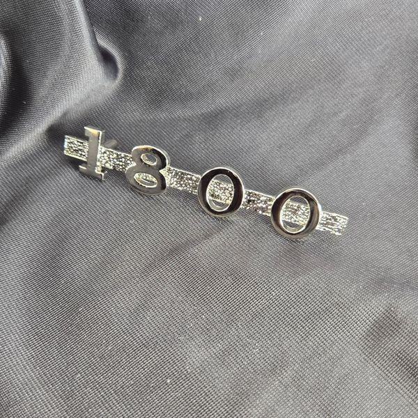 Nickel‑plated MGA 1800 emblem on black cloth background, highlighting polished surface and high‑quality reflective plating.