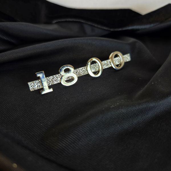 Close‑up of shiny nickel‑plated MGA 1800 emblem on black velvet background, showing crisp lettering and smooth reflective finish.