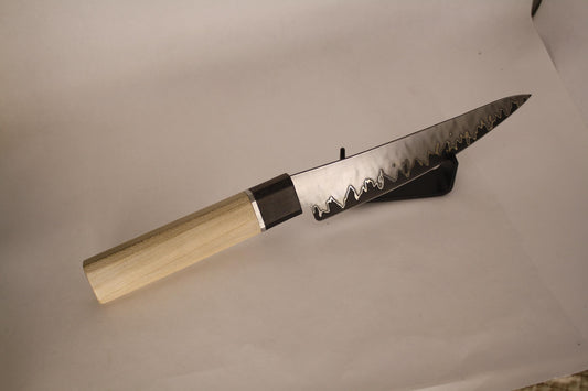 Closeup of San‑Mai knife handle on white background with black stand, showcasing stainless steel spacer detail transitioning from silver maple to Gaboon ebony, echoing nickel layers in blade construction.