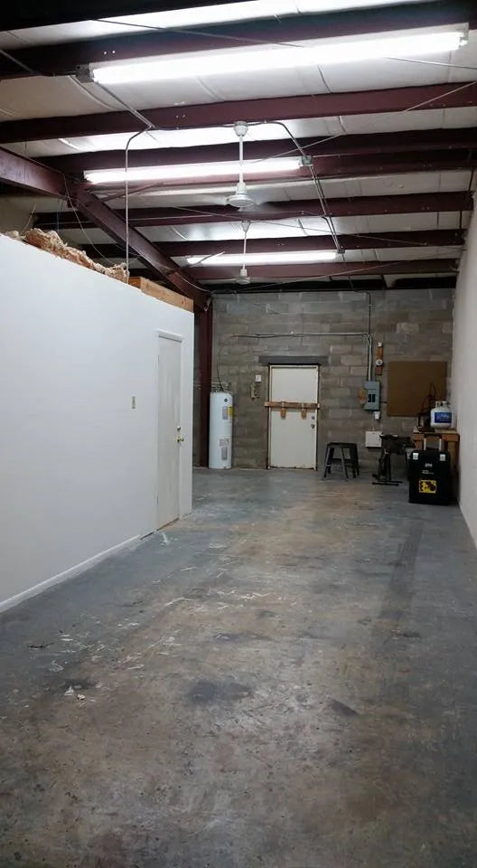 Chris’s workshop shortly after he moved in about 10 years ago — empty concrete floors, exposed ceiling beams, and the wall where his office would later be built.