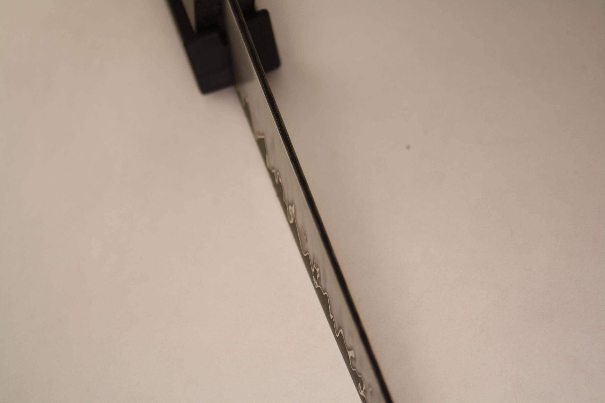 Closeup of San‑Mai blade spine, emphasizing layered construction with 1095 core and visible nickel between stainless cladding for durability and balance.