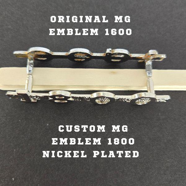 Back view of MGA 1800 emblem next to original 1600 emblem, displaying pinned mounting alignment for precise factory‑style installation.