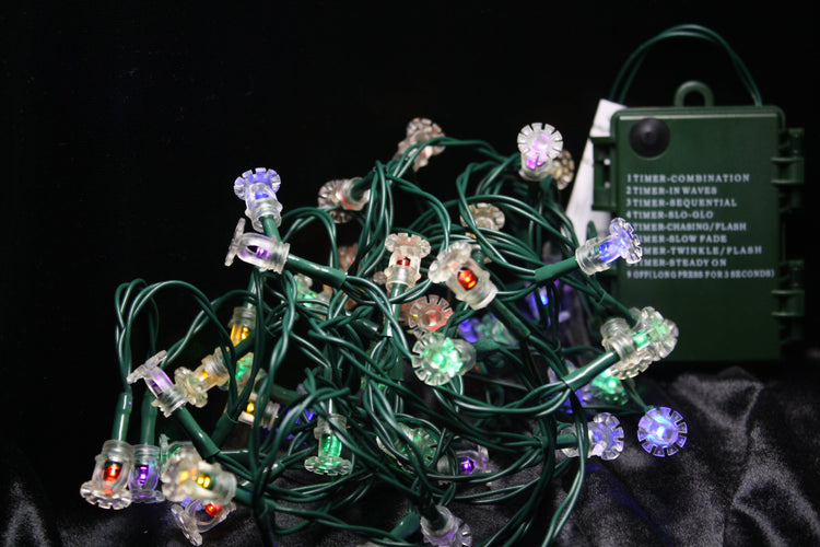 Battery-powered fire sprinkler string lights with clear pendant covers and multicolor LED bulbs in purple, red, yellow, and green on green wire, featuring 8 lighting modes.