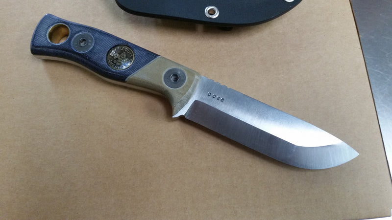 Custom knife made from O‑1 tool steel with handle crafted from Cub Scout uniform micarta, featuring inlaid button as bow‑drill hand socket for primitive fire making. Unique piece blending scouting heritage with functional survival design.