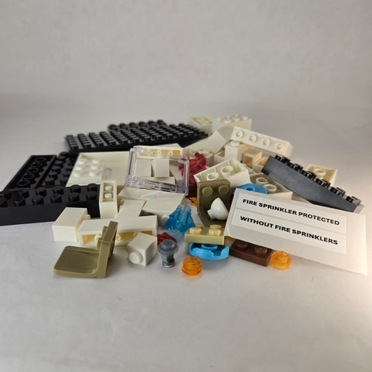 Unassembled mini fire sprinkler demo kit showing all building block pieces and sticker sheet labeled ‘Fire Sprinkler Protected’ and ‘Without Fire Sprinklers.