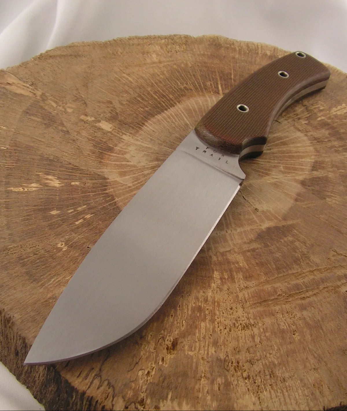 Chris’s first knife sold — an EDC forged from recycled 5160 coil spring steel with a flat‑ground blade and green canvas micarta handle slabs.