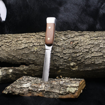 Knife with wooden handle on a log against a black background