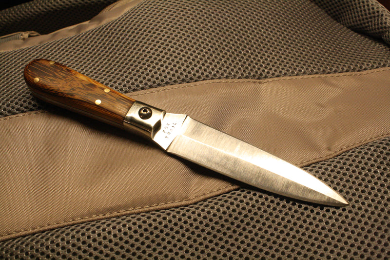 Double‑edged 440 stainless dagger with nickel silver bolsters and marblewood handle, full exposed tang, photographed resting on a car seat.